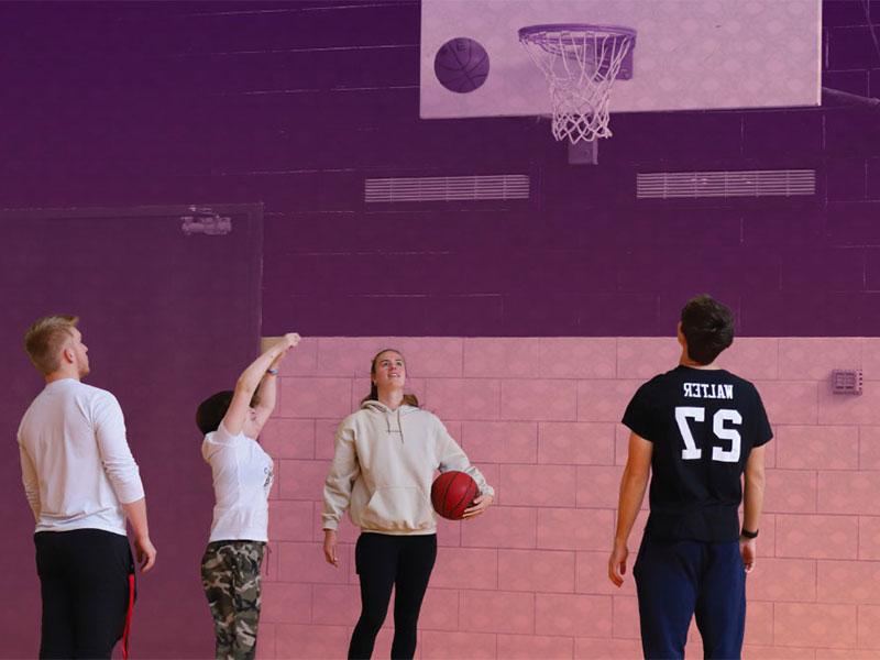 Two women and two men shooting basketballs in gym